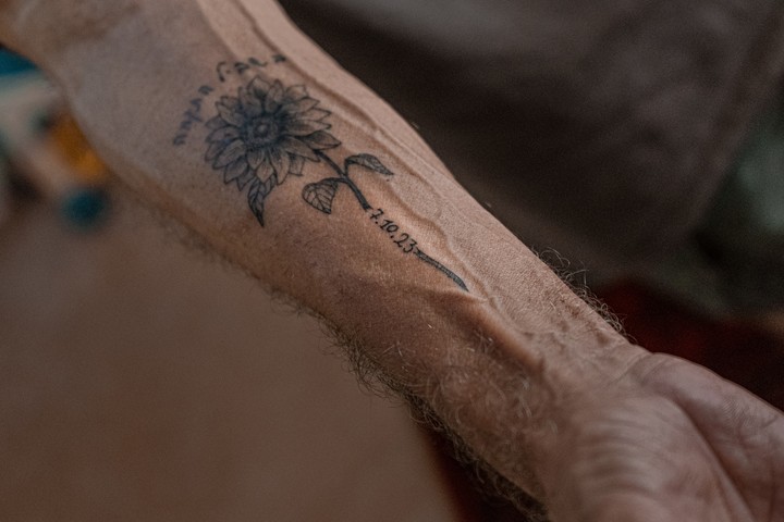 Un tatuaje de un girasol, la fecha del ataque del 7 de octubre y las palabras "En el camino de la esperanza" en el brazo de Daniel Rahamim, portavoz del kibutz pastoral Nahal Oz, el 16 de septiembre de 2026. La imagen del girasol trepando por su antebrazo simboliza un cultivo local y la esperanza, según Rahamim, "porque siempre mira hacia el sol". (Amit Elkayam/The New York Times)