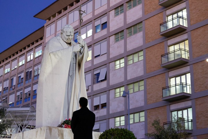 Un sacerdote reza ante la estatua de Juan Pablo II frente al Hospital Agostino Gemelli. Foto ANSA